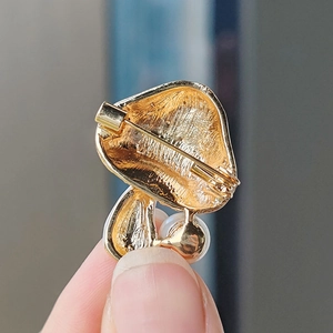 Detail view of the mushroom brooch back with golden texture, pin clasp and pearl accent