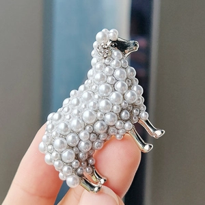 Detail showing hand-held sheep brooch with white pearls and small crystal accents
