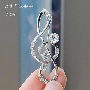 Macro shot of silver musical note brooch with sparkling rhinestones, 2.1 x 5.4cm size