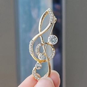 Macro shot of gold treble clef musical note brooch with sparkling crystals and diamonds