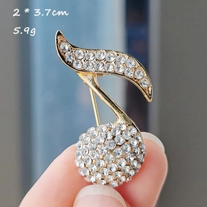 Macro shot of musical note brooch with gold plating and rhinestones, size 2 x 3.7cm
