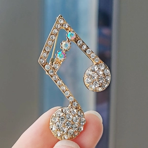 Detail of music note brooch with sparkling clear crystals and iridescent AB rhinestones