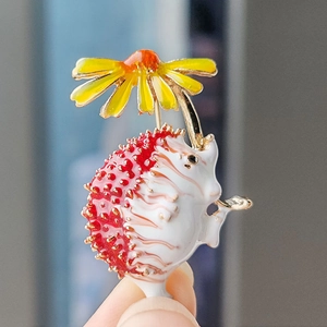 Charming hedgehog brooch pin with red enamel back and golden daisy detail