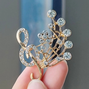 Macro detail of a golden treble clef and flower brooch with sparkling white rhinestones