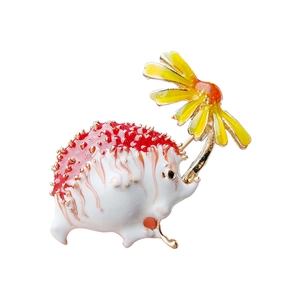 Enamel hedgehog brooch with red back holding a yellow daisy flower in gold plating