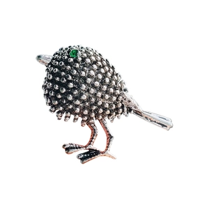 Vintage silver sparrow brooch with textured metal body and sparkling green gem eye