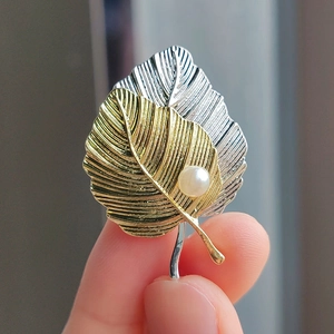 Close-up of luxury ginkgo leaf brooch with silver and gold petals and a pearl detail