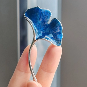 Macro detail of a silver ginkgo leaf brooch with blue gradient marble enamel finish