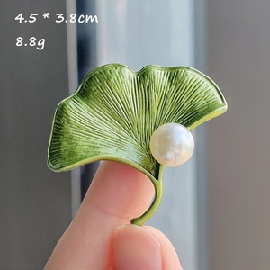 Detail view of ginkgo leaf brooch with green enamel, white pearl, 4.5 x 3.8cm dimensions