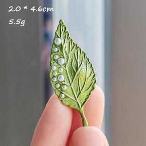 Detail view of leaf-shaped brooch with white pearls, measuring 2.0 by 4.6cm