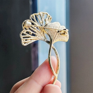 Macro detail of the golden ginkgo leaf brooch back showing secure safety pin clasp