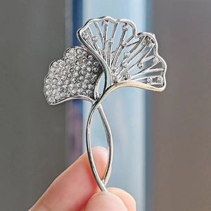 Detail of silver ginkgo leaf brooch with sparkling crystals on elegant suit lapel