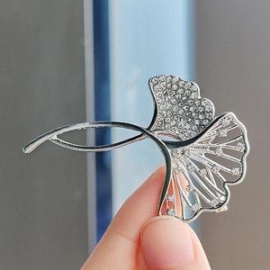 Detailed close-up of a silver ginkgo leaf brooch with sparkling pavé rhinestones
