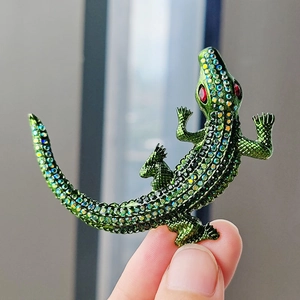 Macro detail of vintage green crocodile brooch with colorful rhinestones and red eyes