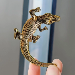 Golden crocodile brooch featuring intricate honeycomb hollow design and secure safety pin