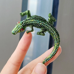 Macro shot of an intricate crocodile brooch with green rhinestones and red jewel eyes
