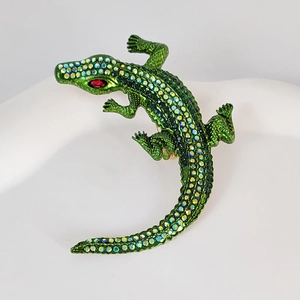 Close-up of green crystal crocodile brooch with rhinestone detail and ruby red eyes
