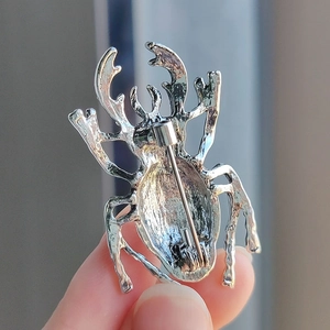 Back view of silver beetle brooch showing the secure pin fastener and metal texture