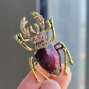 Macro shot of beetle brooch with purple enamel wings and sparkling inlaid gemstones