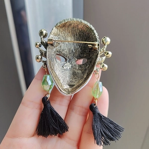 Vintage alloy mask brooch with green faceted beads and black tassels, back pin view