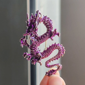 Handheld view of a purple enamel Chinese dragon brooch with detailed gold scales
