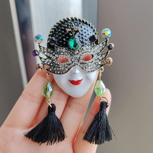 Exquisite masquerade mask brooch with white rhinestones and black tassels held by hand