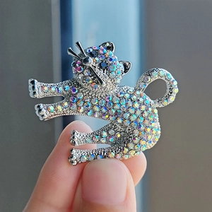 Close-up of a silver cat brooch with colorful rhinestones held between fingers