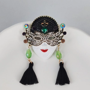 Detail of Venetian mask brooch with sparkling rhinestones, green gems, and black silk tassel