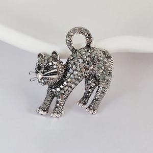 Macro detail of silver cat brooch featuring dark grey crystals and black stone eyes