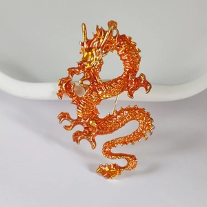 Detailed macro shot of an orange enamel dragon brooch with intricate gold plating textures