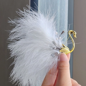 Detailed view of swan brooch with elegant white feathers and gold-plated finish