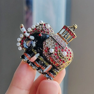 Handheld vintage elephant brooch with colorful rhinestones and white faux pearls
