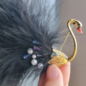 Vintage swan brooch featuring black feathers, white pearls, and crystals on golden alloy