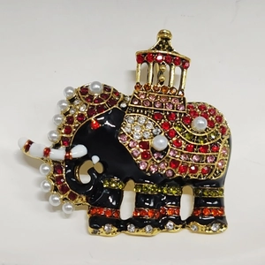 Close-up of golden elephant brooch with black enamel, colorful crystals and pearls