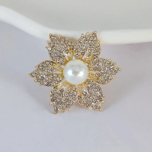 Détail de la broche fleur dorée avec perle centrale et pétales sertis de strass