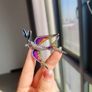 Close-up of blue swallow brooch featuring colorful enamel wings and sparkling rhinestones