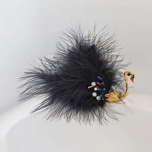 Detailed close-up of a black swan brooch with feathers, golden alloy, and white pearls