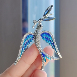 Detailed close-up of a silver swallow brooch with blue enamel wings and crystals