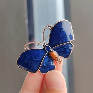 Nahaufnahme einer blauen Emaille-Schmetterlingsbrosche mit goldenem Rahmen