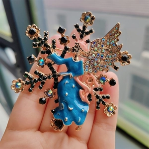 Detailaufnahme einer Vintage-Engelsbrosche mit blauen Sternenflügeln in der Hand