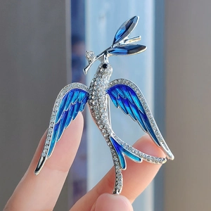 Detailed view of silver bird brooch with blue enamel wings and sparkling zircon inlay