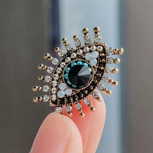 Vintage gold Evil Eye brooch with freshwater pearl, blue rhinestones, and black centerpiece
