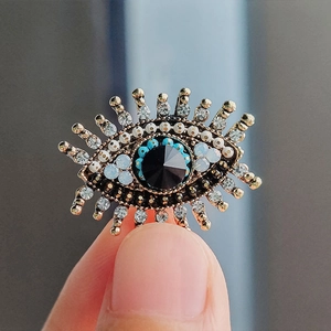 Macro shot of evil eye brooch with blue beads, black gemstone and vintage gold details