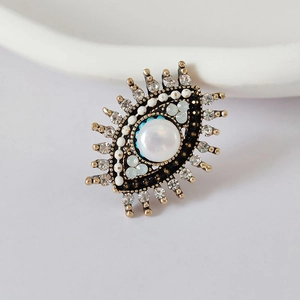 Macro view of evil eye brooch featuring a large pearl center and radiant white rhinestones