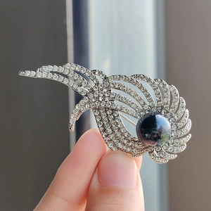 Elegante spilla ad ala d'angelo con strass argentati e una grande perla scura
