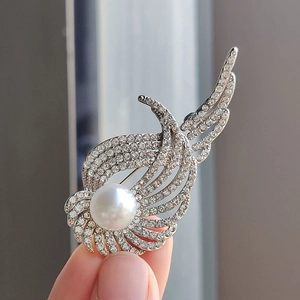 Elegante spilla ad ali d'angelo d'argento con cristalli scintillanti e perla in mano