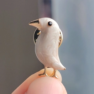 Elegant bird brooch with white pearlescent enamel finish and gold-toned metal accents