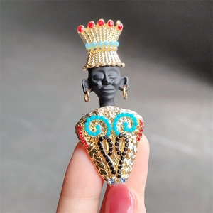 Macro shot of exotic vintage brooch featuring a tribal queen with colorful crystals