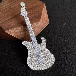 Macro shot of sparkling guitar brooch with white rhinestones on dark wood stand