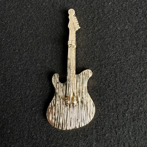 Macro view of the textured golden guitar brooch back with secure pin clasp detail